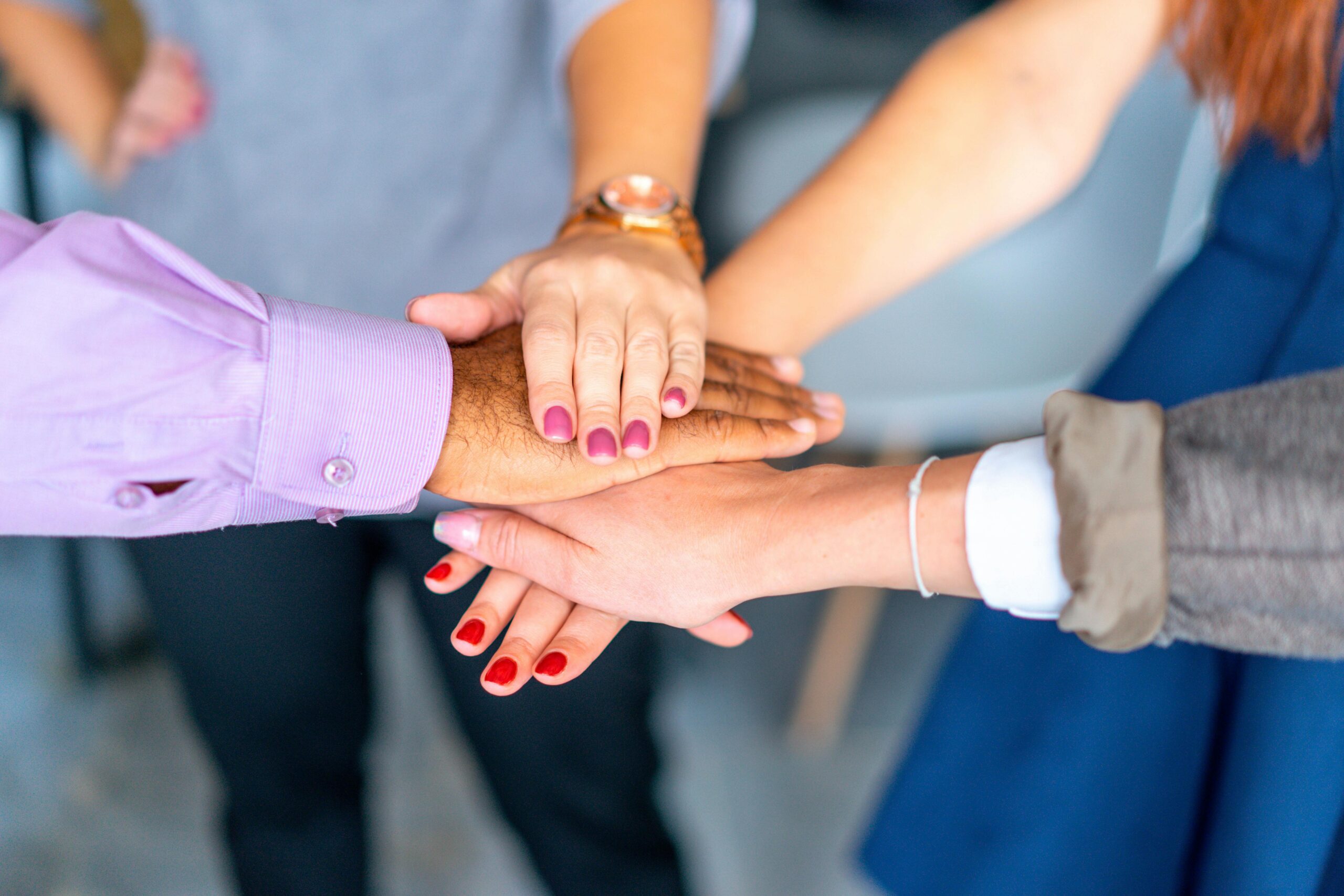 Close-up of diverse hands joined in a symbol of unity and teamwork.